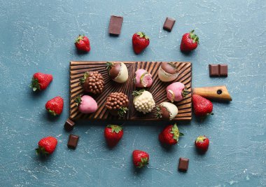 Çikolata kaplı çilekli ahşap tahta tahta ve koyu arkaplanda taze böğürtlen.