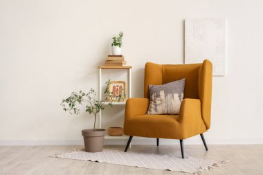 Yastıklı koltuk, kitaplı raf ünitesi ve oturma odasının iç tarafında dekoratif zeytin ağacı.