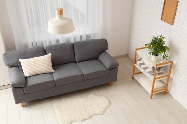 Oturma odasının içinde yastıklı ve raflı rahat bir kanepe.