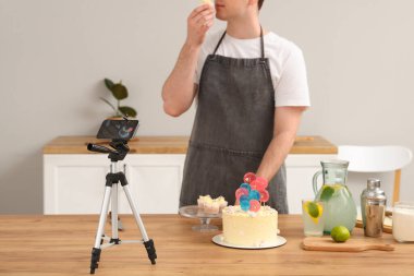 Pasta ve kekle genç adam mutfakta yemek videosu kaydediyor.