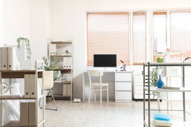 Doktorun çalışma yeri ve raf üniteleri olan bir tıp bürosu.