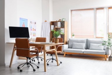 Doktorun çalışma yeri, kanepesi ve raf ünitesi olan bir tıp bürosu.