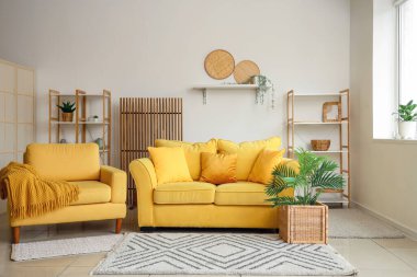 Rahat bir kanepe, oturma odasındaki sepetin içinde ekose ve çiçekli bir koltuk.