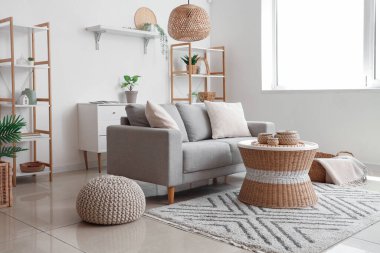 Yastıklı rahat kanepe, hasır sehpa, puf ve ekoseli sepet.