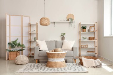 Yastıklı rahat kanepe, hasır sehpa, puf ve ekoseli sepet.