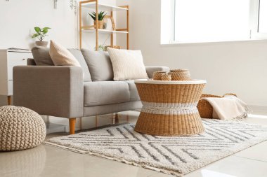 Yastıklı rahat kanepe, hasır sehpa, puf ve ekoseli sepet.