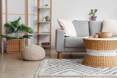 Yastıklı rahat kanepe, hasır sehpa, puf ve saksı.