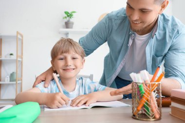 Babasıyla birlikte evde ödev yapan sevimli bir çocuk.