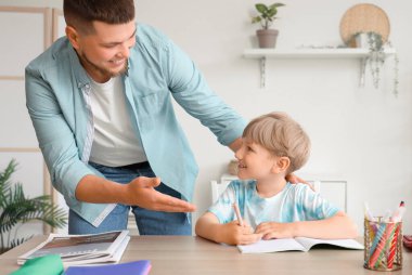 Genç adam ve küçük oğlu evde ödev yapıyorlar.