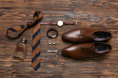 Parfüm şişeli erkek ayakkabıları ve ahşap arka planda aksesuarlar.