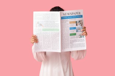Pembe arka planda gazetesi olan genç bir Afro-Amerikalı kadın.
