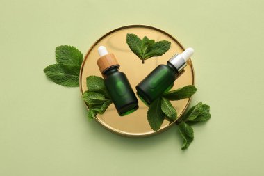 Yeşil zemin üzerinde gerekli yağ, altın tepsi ve nane yaprakları