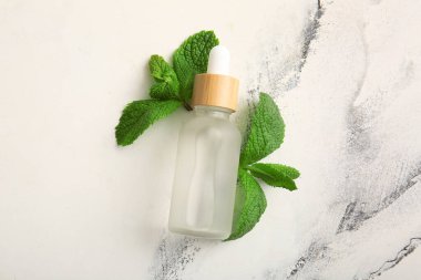 Mermer zemin üzerinde gerekli yağ ve nane yaprakları, yakın plan.