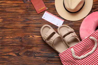 Seyahat yastığı, pasaport, bilet ve tahta arka planda plaj aksesuarları.