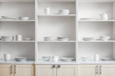 Mutfakta farklı temiz tabaklar olan beyaz raf ünitesi.