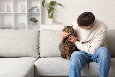 Evdeki kanepede oturan sevimli kedili genç adam.