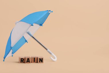 Mini şemsiye ve kelime yağmuru kahverengi arka planda tahta küplerden yapılmış.