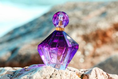 Okyanusun yakınındaki taşın üzerinde bir şişe lüks parfüm.