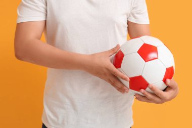 Sarı arka planda futbol topu olan genç çocuk, yakın plan.