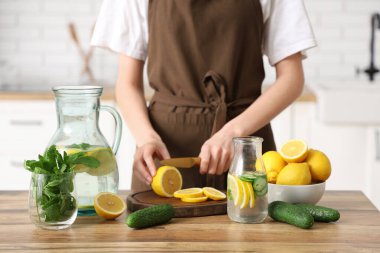 Mutfakta naneli su hazırlamak için limon kesen genç bir kadın.