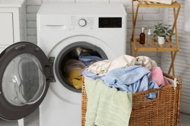 Çamaşır makinası ve kirli çamaşırlarla dolu sepet.