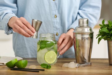 Evde elinde ölçü kabı ve bir kavanoz taze mojito olan genç bir kadın var.