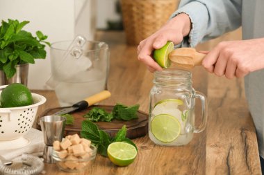 Genç bir kadın evde taze mojito ile kavanoza limon sıkıyor.