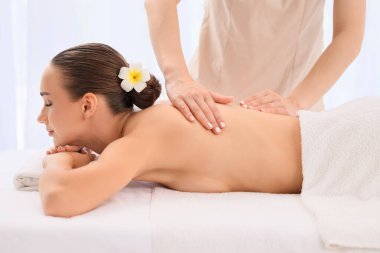 Güzeller güzeli genç bir kadın spa salonunda terapist tarafından masaj yaptırıyor.