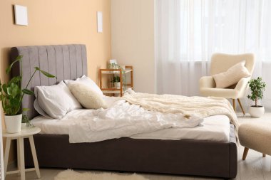 Rahat yatak, koltuk, puf ve bitki yatak odasında.