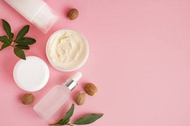 Pembe arka planda tereyağlı kavanoz ve kozmetik ürünleri