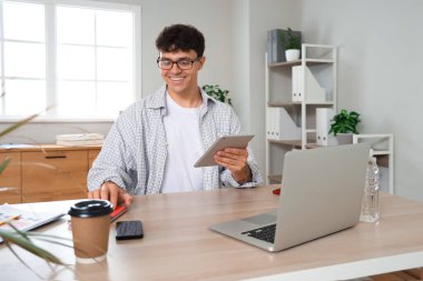İş yerinde gözlüklü, tablet kullanan, modern bilgisayarlı bir erkek muhasebeci.