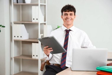 İş yerinde dosya ve dizüstü bilgisayarla çalışan erkek muhasebeci.