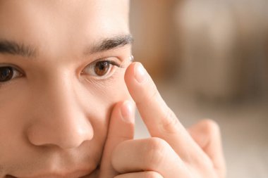 Genç adam evde kontak lens takıyor, yakın plan.
