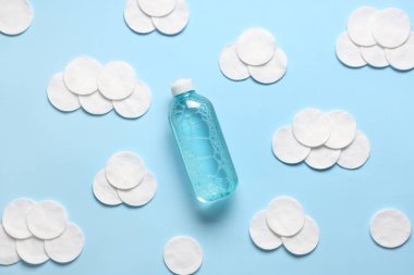 Bir şişe mikiler suyu ve mavi arka planda bulut şeklinde pamuk pedler.