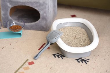 Litter box for cat with scoop on carpet in living room clipart