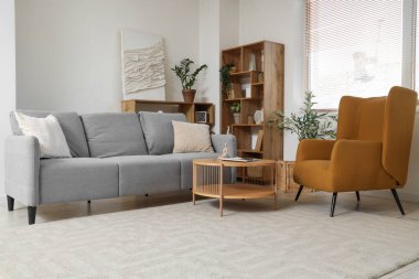 Gri kanepesi, koltuğu ve penceresi olan oturma odası.