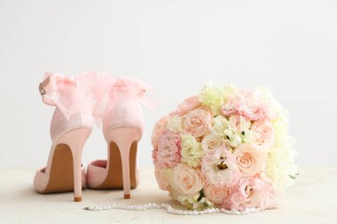 Güzel düğün buketi, kolye ve parlak arka planda gelin ayakkabıları.