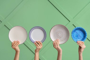 Yeşil arkaplanda boş tabakları tutan eller