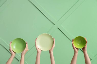 Yeşil arkaplanda boş tabakları tutan eller