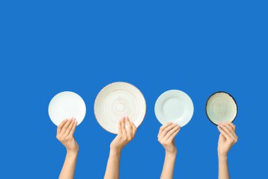 Mavi arkaplanda boş tabakları tutan eller