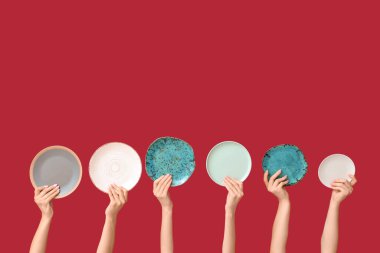 Kırmızı arkaplanda boş tabakları tutan eller