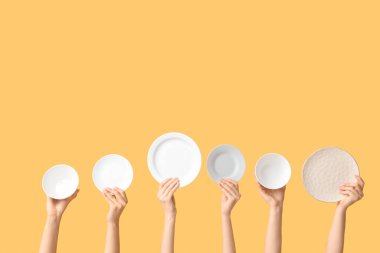 Sarı arkaplanda boş tabakları tutan eller