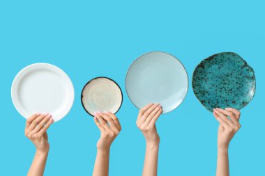 Mavi arkaplanda boş tabakları tutan eller