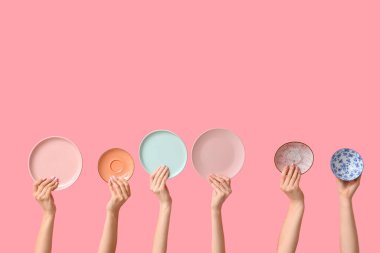 Pembe arka planda boş tabakları tutan eller