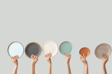 Açık arkaplanda boş tabakları tutan eller