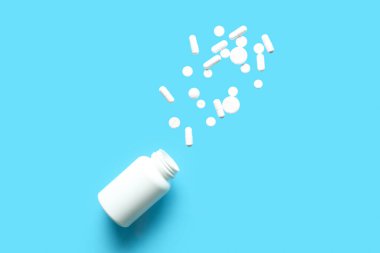 Mavi arka planda beyaz uçma hapları olan bir şişe. Üst görünüm