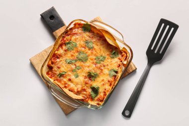 Hafif arka planda lezzetli enchilada ve spatula ile pişirme yemeği