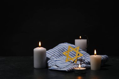 Prisoner uniform, burning candles and Star of David on dark background. Holocaust Remembrance Day clipart