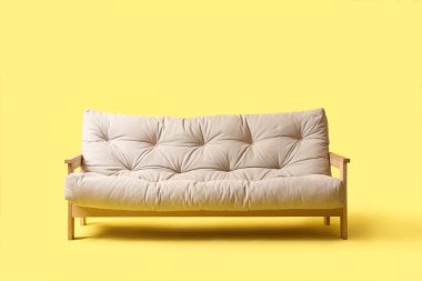 Sarı arka planda rahat beyaz kanepe