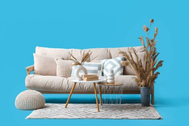 Rahat beyaz kanepe, kahve masası ve mavi arka planda otlar.